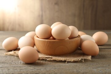 Raw chicken eggs in bowl on wooden table, closeup