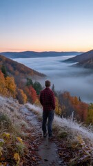 Obraz premium Autumn Mountain Sunrise Landscape with Man Standing on Frosty Trail Above Misty Valley, Scenic Nature Adventure, Fall Colors
