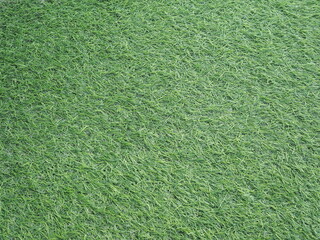 Artificial green grass background. Top view of green lawn. Artificial turf. Surface of green synthetic fibers. Made from synthetic fibers, two types of plastic, Polyethylene (PE) and Polypropylene (PP