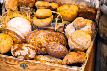 A large selection of wheat and rye breads in a wooden chest in the village. Baked goods made from flour at a village bakery, close-up