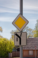 European Priority Road Sign Showing Main Road Turning Left Upwards with Side Roads Straight and Down