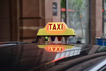 a yellow taxi cab reflected by the roof of a car