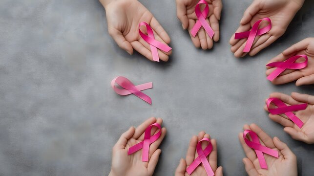 Flat lay of multiple pink ribbons arranged in a circle on a gray surface, symbolizing awareness and support for breast cancer, creating a meaningful visual impact