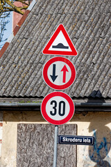 European Road Signs on Skroderu Iela Indicating Bump Ahead, Oncoming Traffic Priority and Speed Limit 30