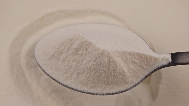 Close-up of a spoon with fine collagen powder on a smooth background. Concept of dietary supplement, protein nutrition and wellness product for health and beauty industries, self care.
