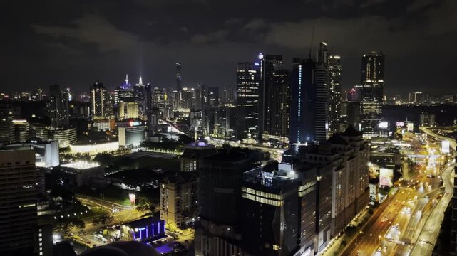 A nighttime view of Kuala Lumpur with illuminated skyscrapers, highways, and glowing city lights, showcasing the modern urban skyline of Malaysia