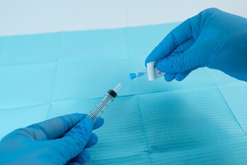 Attaching a needle to a syringe after opening the packaging, before full removal, using gloved hands over a sterile field.