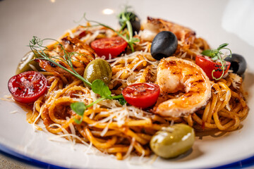 Closeup of shrimp pasta with olives and tomatoes