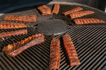 Grilled ribs cooking on round barbecue grill. Delicious barbecue pork ribs with crispy dry rub seasoning placed on circular grill ready for serving.