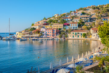 Sunny Day at Assos Village: Wide View of the Harbor, Colorful Waterfront Buildings, and Beach Activities, Kefalonia