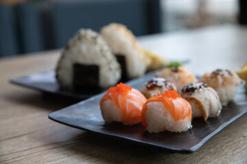 Temarizushi or Japanese rice balls with Onigiri or Japanese rice triangle served on on the black plate in the restaurant Temari zushi with seafood. Kimbab or gimbap - rice triangle. Selective focus.