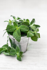 Mint in small basket on natural wooden background, peppermint, selective focus, close up