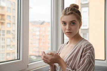 A young woman drinking morning tea on a balcony, selective focus. Real photo