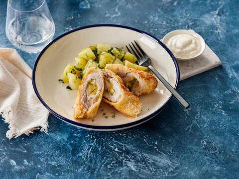 Enjoy a delicious plate of golden-brown chicken kiev, stuffed with herbs and garlic butter, accompanied by soft potato pieces. Perfect for a satisfying meal