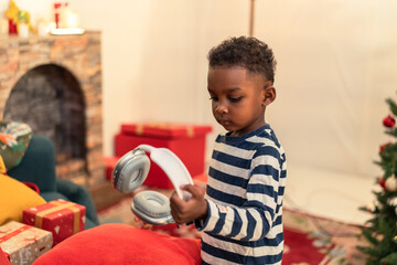 A cute African American boy standing and holding stuff in the living room with decoration...