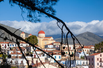 Galaxidi town, panoramic view of this traditional Greek town  through tree branches and the Greek Orthodox church of Saint Nicolaus atop the hill.