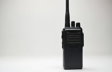 Black handheld two-way radio with long antenna and knobs on top. Device is isolated on white background. Portable communication equipment for security and emergency services.