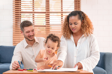Happy parents playing with their adorable baby at home. Mom and dad looking at their baby who drawing on paper with pencil in cozy living room. Creative education. Early development