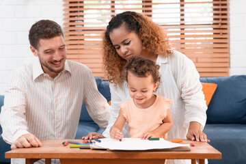 Happy parents playing with their adorable baby at home. Mom and dad looking at their baby who drawing on paper with pencil in cozy living room. Creative education. Early development