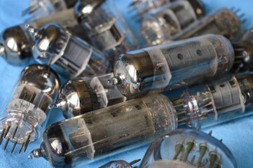 vintage vacuum tubes on blue background, retro electronic components used in radios and amplifiers, close up of glass valves with metal pins