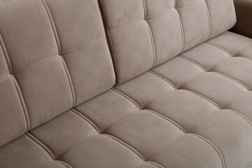a close up of a beige sofa with tufted upholstery and neatly stitched square patterns.