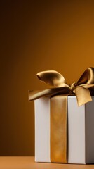 Elegant white gift box with a luxurious golden ribbon against a warm golden background, perfect for celebrations