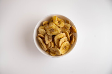 Banana chips in a bowl on a white background. Diet sweets.