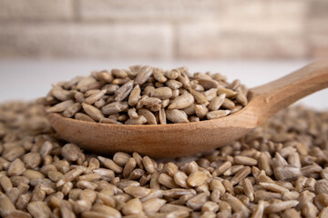 shelled sunflower seeds in a wooden spoon  on a white background