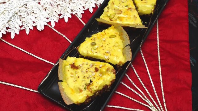 Malai Ghevar or Ghewar on a black plate with festive red background. video clip