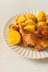 A delicious plate showcases a portion of baked rabbit alongside tender, golden roasted potatoes. The rabbit appears well-seasoned, with a crispy skin, while the potatoes are perfectly cooked