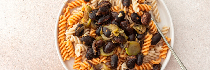 Savor the combination of gluten-free pasta with stewed beans and zucchini, a delightful vegetarian option that's as nutritious