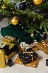 Luxurious gold and black gift boxes arranged beneath a Christmas tree, illuminated by glowing candles and adorned with elegant decorations, creating a chic holiday ambiance