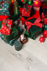 A festive display of green and red gift boxes under a beautifully decorated Christmas tree, complemented by candles and traditional ornaments, evoking warmth and holiday cheer