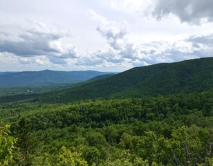 Panoramic view of lush green mountains and forests under a partly cloudy sky