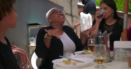 Family and friends enjoying laughter and food at a backyard lunch, cheerful and casual atmosphere...