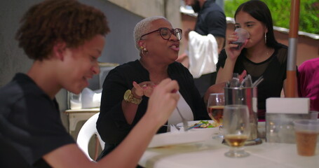 Family and friends enjoying laughter and food at a backyard lunch, cheerful and casual atmosphere with bonding moments around a table