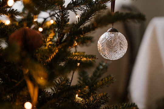 Close-up of an aesthetic minimalistic Christmas tree with baubles and warm fairy lights, festive spirit, cozy winter holidays. Warm tones and coziness