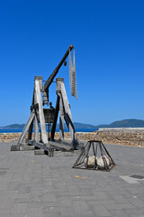Medieval trebuchet at the Belvedere viewpoint in Alghero. Ancient catapult with stone balls for it. Alghero, Satdinia, Italy