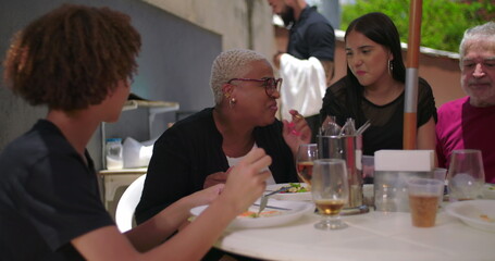 Family and friends enjoying laughter and food at a backyard lunch, cheerful and casual atmosphere with bonding moments around a table