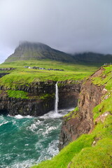 Scenic Mulafossur Waterfall Falling into the Ocean, Showcasing the Natural Beauty of the Faroe Islands