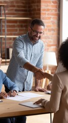 Business meeting with diverse team members shaking hands in a modern office setting with warm lighting