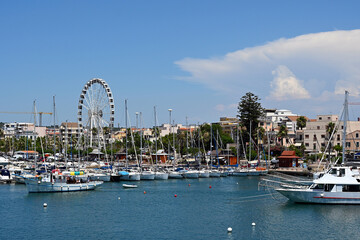 Alghero, Sardegna, Italy. Alghero marina with boats and yachts. Boats in Alghero harbour, coastal buildings and ferry wheel