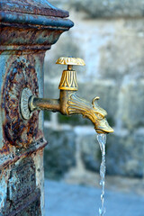 Drinking fountain on street of Alghero, Sardegna, Italy. Close-up of a decorative old faucet with flowing water