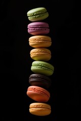 Vertical row of colorful macarons stacked in mid-air on black background