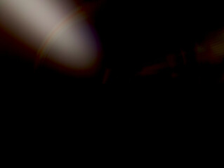 Minimal dark abstract background with a subtle, warm lens flare effect and deep black copy space for cinematic text overlay or high-end product presentation