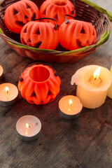 Autumn Pumpkins with Candles – Halloween Decoration. Cozy Halloween scene with autumn pumpkins, candles, and festive miniatures in a basket. Rustic wooden table and soft mysterious daylight create sea