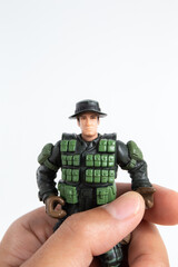 Boy hand holding mini toy soldiers on white background.