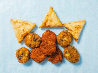 Indian samosa, bhajis and pakoras on blue background. Party sharing finger food variety made from fine products and aromatic spices. Special orient vibe. Tasty snack selection.
