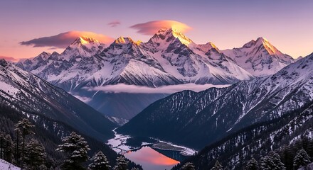 Snowy mountain range at sunset with clouds over peaks and a valley with a lake reflecting the sky