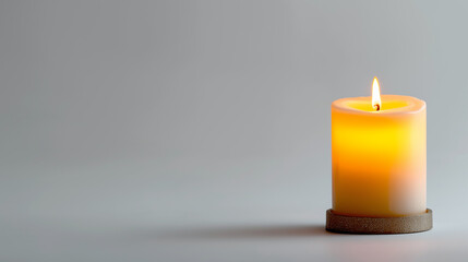 A single lit pillar candle casting a warm glow and soft shadow on a plain gray background